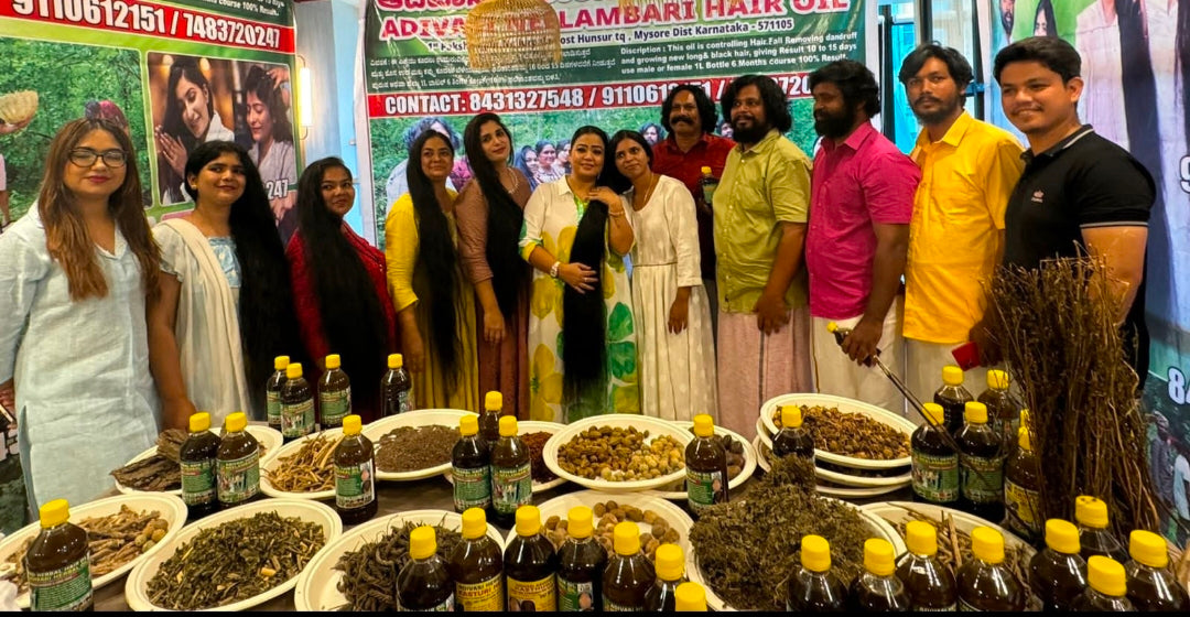 Group of people standing around a table with various Hakki-Pikki_Herbal_Hair_Oil  bottles and bowls, with promotional banners in the background.