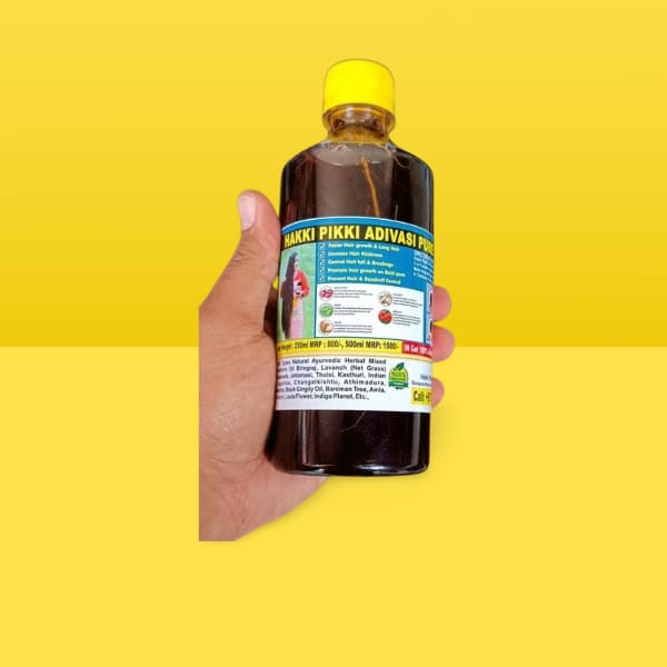 Hand holding a bottle of 'Hakki Pikki Adivari' product against a yellow background