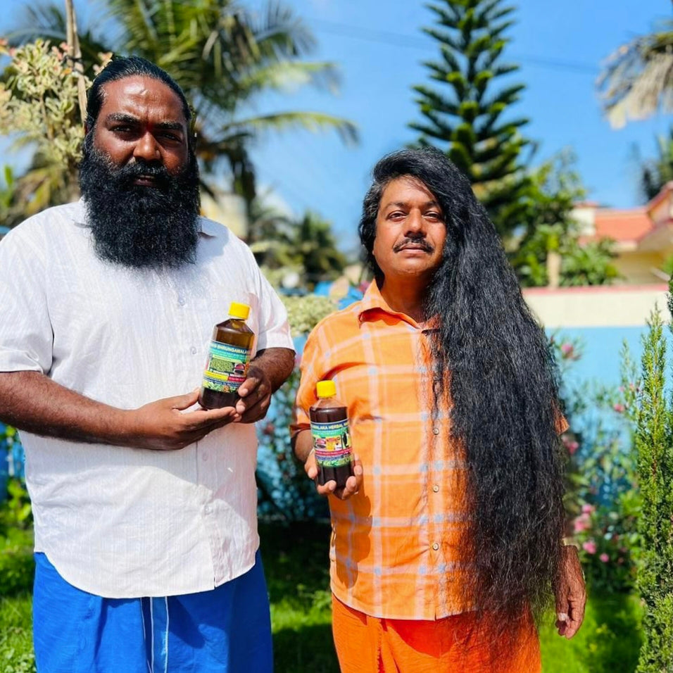 Two men, one with a beard and the other with long hair, holding Hakki-Pikki_Herbal_Hair_Oil bottles outdoors.