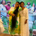 Two women standing in front of a movie poster with a group of people.