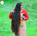 Woman with long hair holding a  HAKKI PIKKI ADIVASI HERBAL HAIR OIL
bottle outdoors