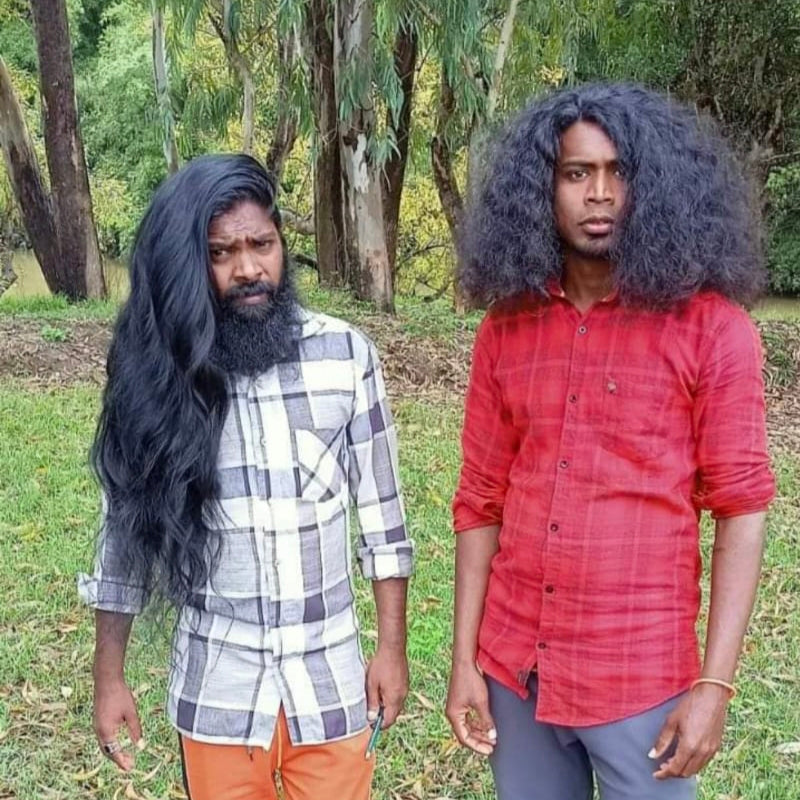 Two individuals standing outdoors with trees in the background