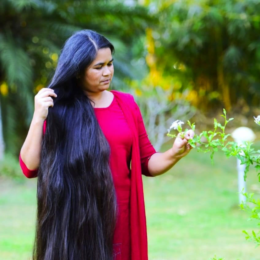 Woman with long black hair holding a plant in a natural setting