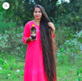 Woman with long hair holding a Hakki-Pikki_Herbal_Hair_Oil bottle outdoors