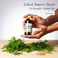 Hand holding a bottle of hair oil with herbs on a wooden surface and text promoting natural hair care.