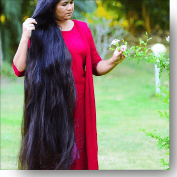 Woman with long black hair wearing a red dress, standing outdoors.