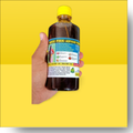 Hand holding a bottle of 'Hakki Pikki Adivasi' with a yellow background
